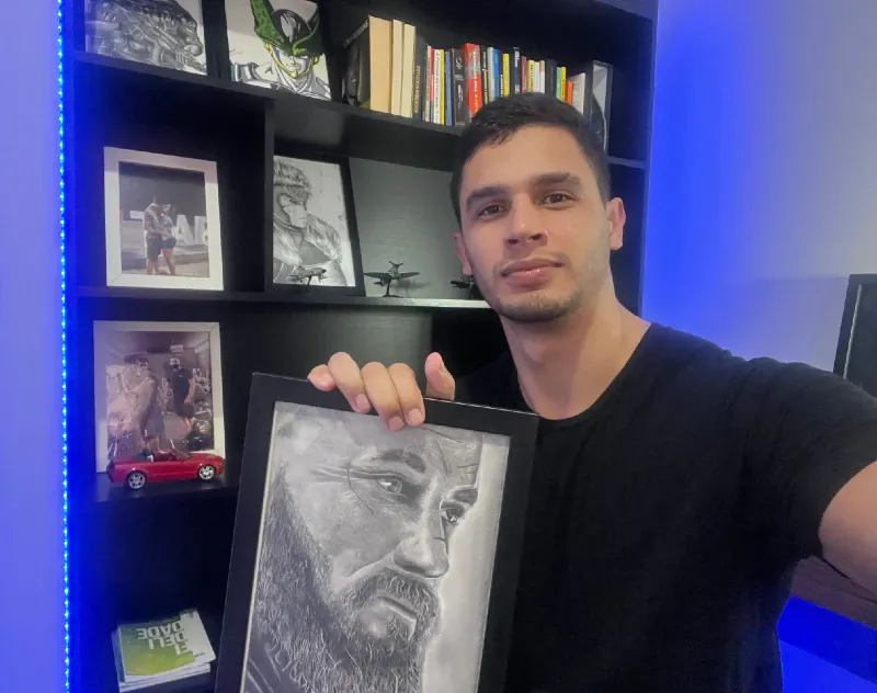 Bruno Brito, fundador da Line Art, segurando um retrato realista a grafite que ele mesmo desenhou