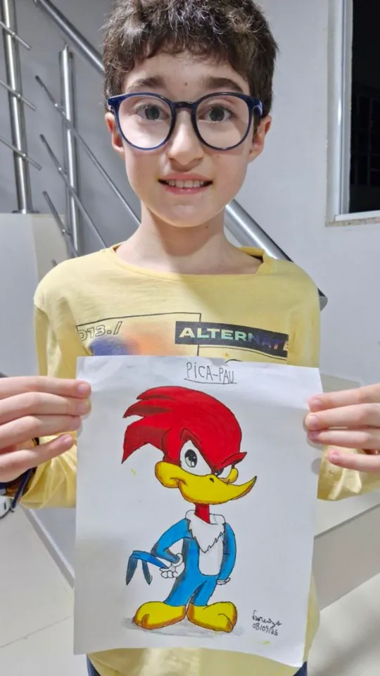 Aluno do Clube Line Art sorrindo e exibindo o desenho que fez na aula ao vivo