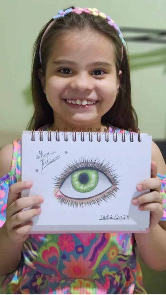 Criança exibindo, orgulhosa, o desenho que fez na aula ao vivo do Clube Line Art