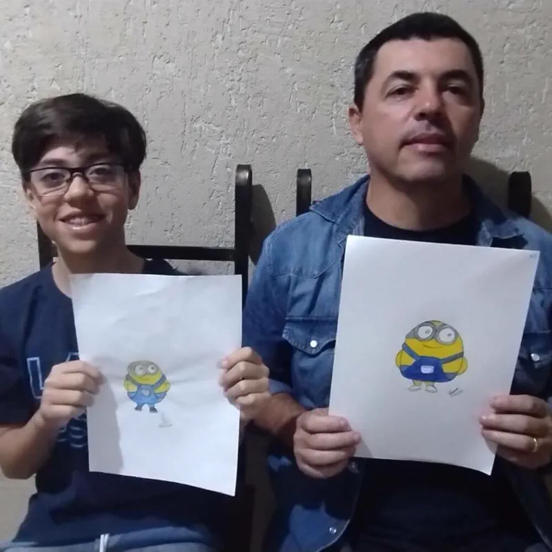 Alberto Ferreira ao lado do filho Vinicius, ambos mostrando desenhos dos Minions