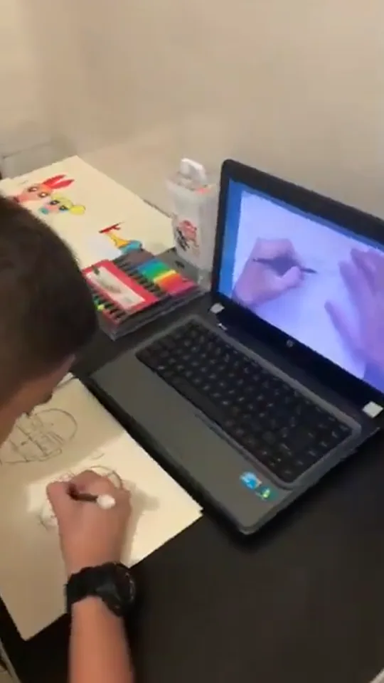 Aluno Daniel, 12 anos, desenhando em casa durante o encontro ao vivo, filmado pela mãe